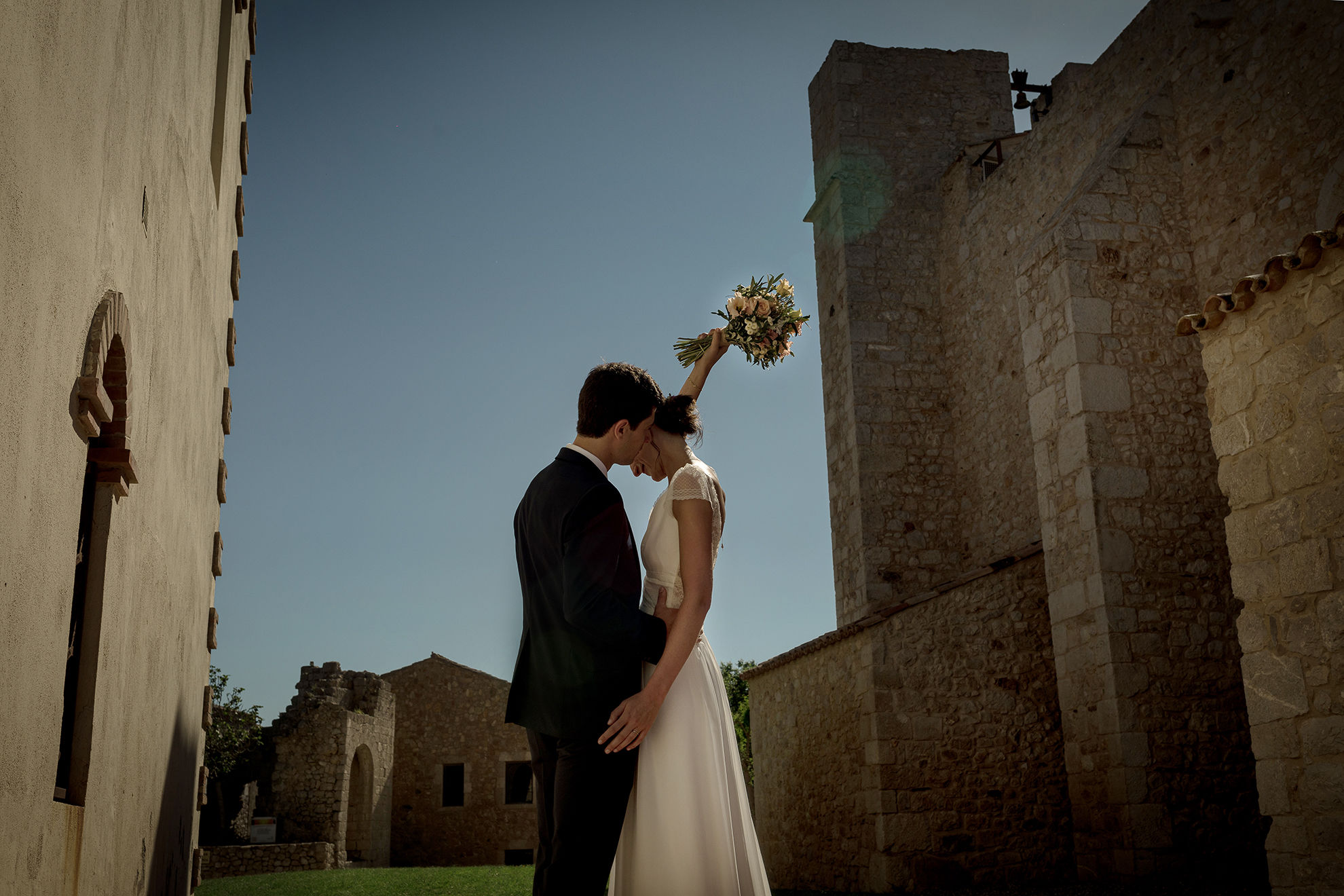 Pareja de novios en la iglesia de Empuries,la novia sostiene el ramo en alto